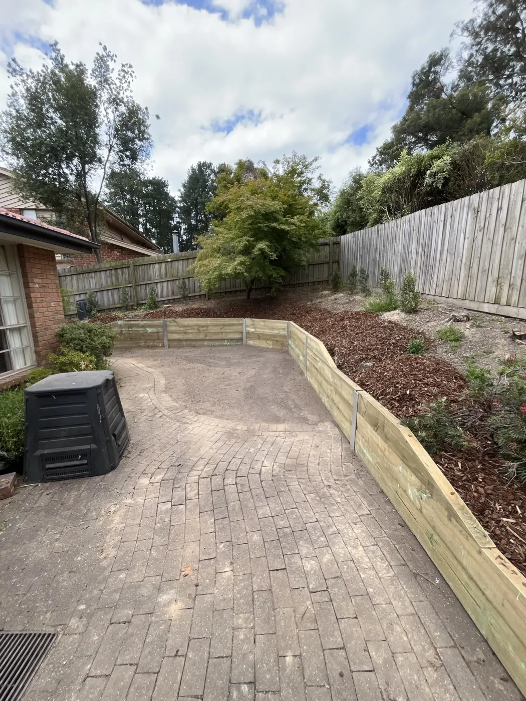 Timber sleeper retaining wall beside a paved driveway